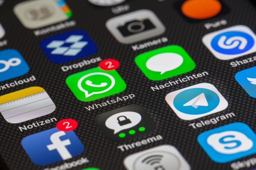 A close-up of a smartphone screen showing various app icons, including WhatsApp with two unread messages, Facebook, Telegram, Dropbox, and others.